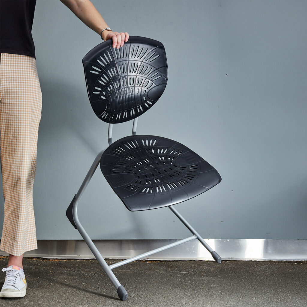 Person holding a black Bodyfurn.Flex sled chair with ventilated seat and backrest