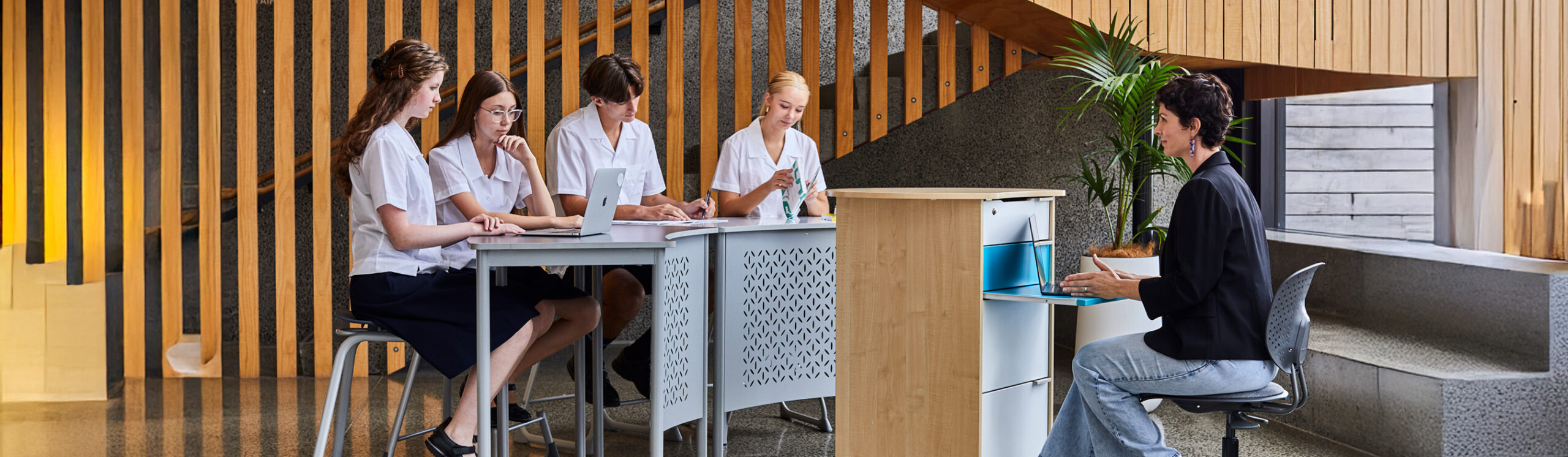 Students and teacher collaborating in a modern learning space using Furnware tables, stools and mobile storage furniture.