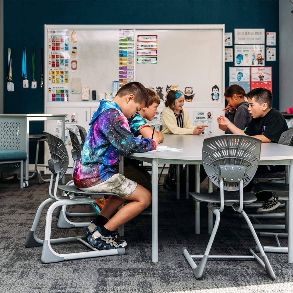 Primary school students working collaboratively in a modern classroom with Furnware Bodyfurn.Flex chairs and learning tables