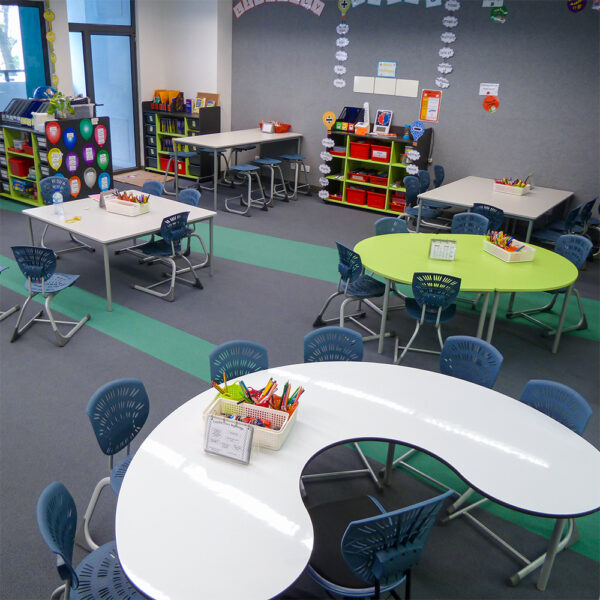 Curved and rectangular group tables with blue Bodyfurn chairs and low classroom storage at Kowloon Primary.