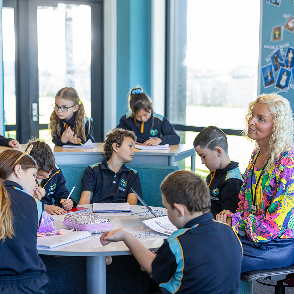 Teacher working with students around a shared table with curved upholstered seating at Putaruru Primary.